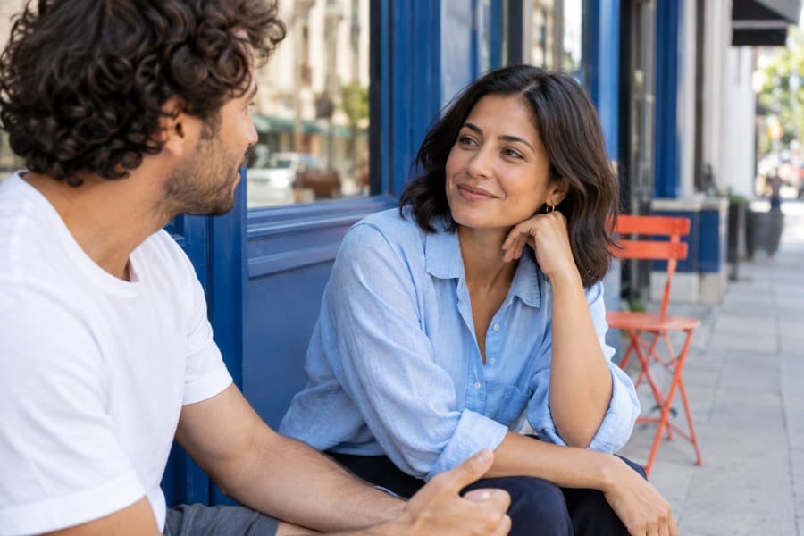 Two adults having an attentive conversation outside a city café